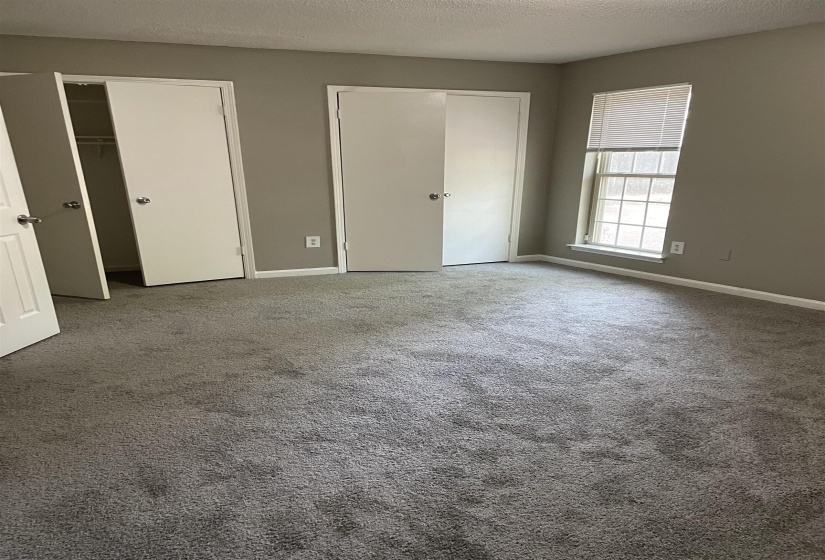 Unfurnished bedroom featuring two closets, carpet flooring, and a textured ceiling