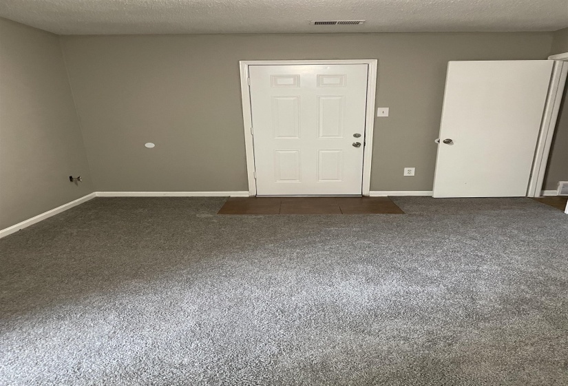 Carpeted spare room featuring a textured ceiling and baseboards