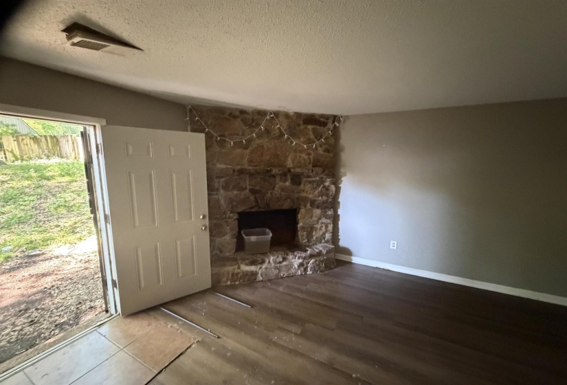 Stone-clad fireplace with a hearth, dark wood-finish flooring, and light-toned wall paint