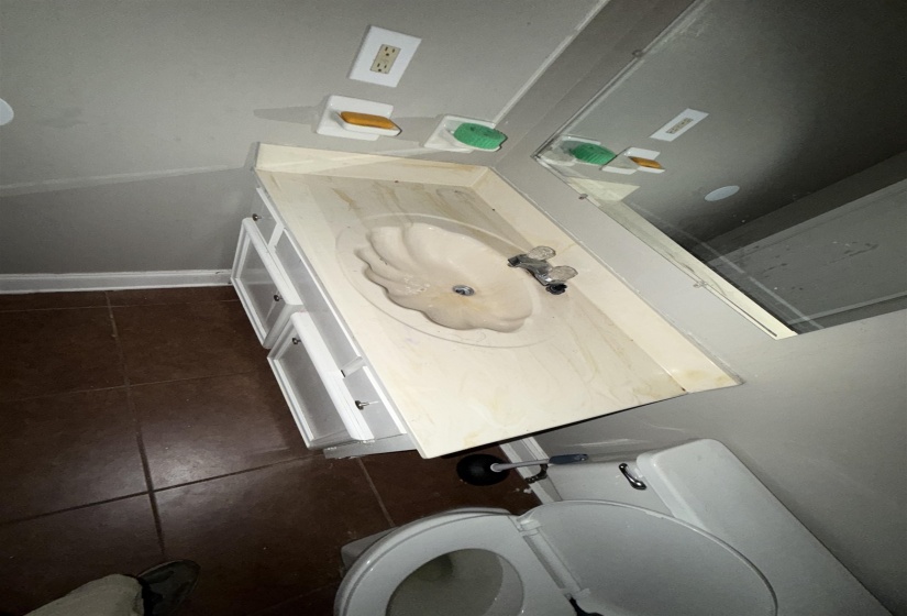 Bathroom featuring a vanity with an integrated sink, dual-handle faucet, white cabinetry, and a wall-mounted mirror