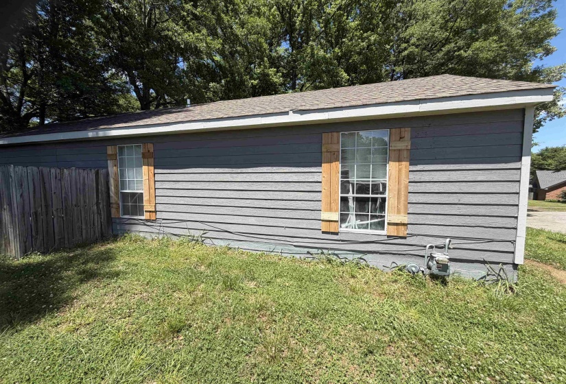 Gray horizontal siding exterior with two windows featuring light wood-tone shutters