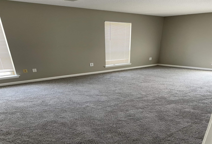 Carpeted spare room featuring a textured ceiling and baseboards