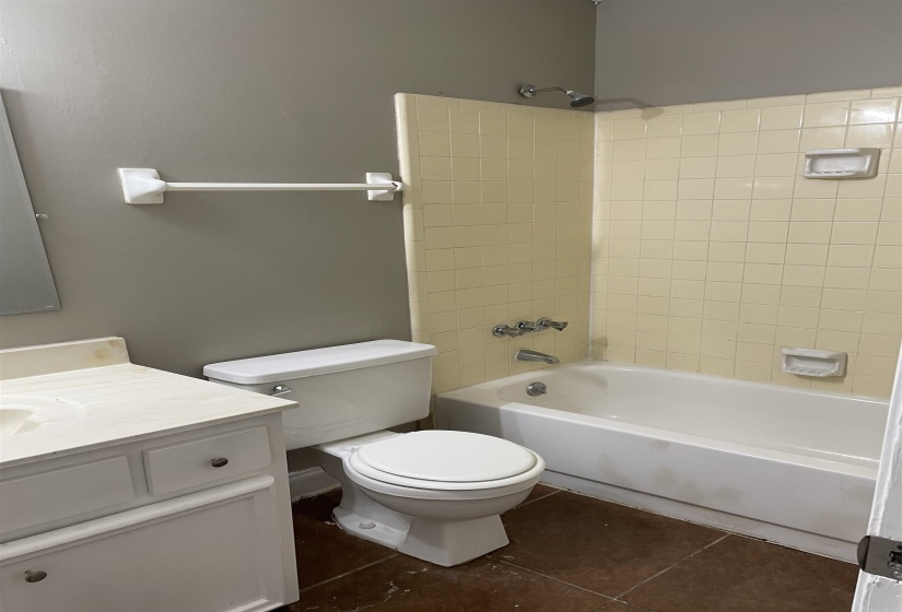 Full bathroom featuring washtub / shower combination, dark tile patterned flooring, and vanity