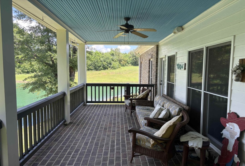 Spacious covered porch featuring brick flooring, a beadboard ceiling, a ceiling fan, and multiple windows