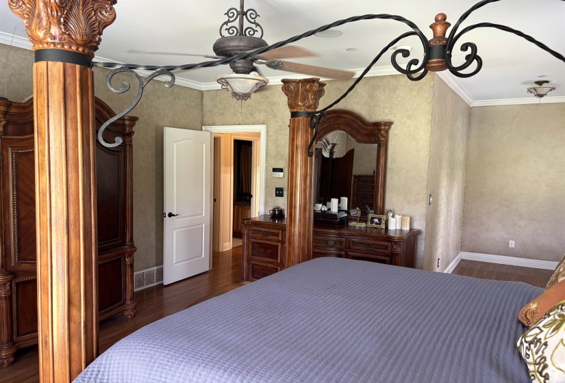 Spacious room featuring wood-finish flooring, crown molding, and a decorative ceiling fan with light fixture