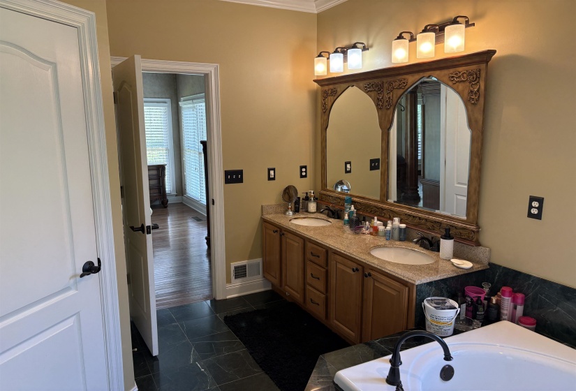 Double vanity with granite countertop, dual undermount sinks, and an ornate framed mirror