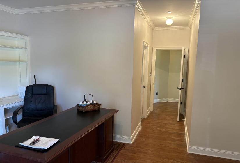 Interior space featuring a built-in shelving unit, crown molding, and wood-finish flooring