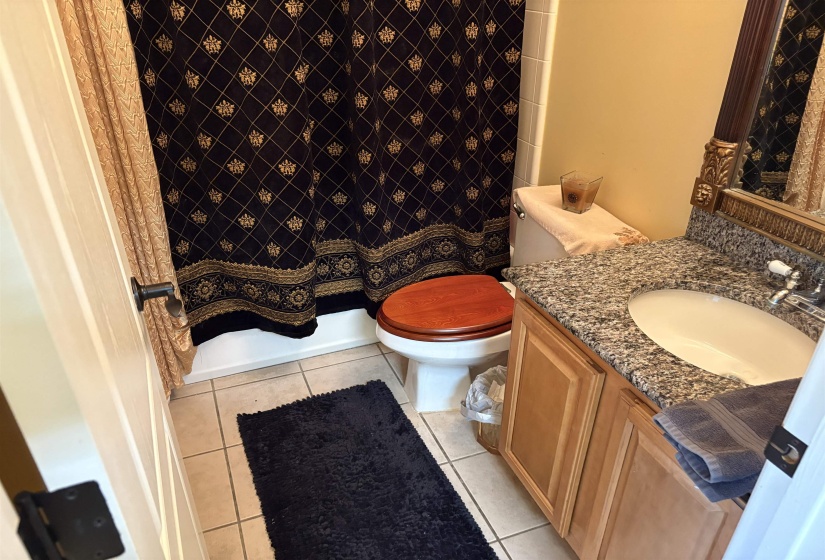 Bathroom featuring a single vanity with a granite countertop, undermount sink, and wood cabinetry