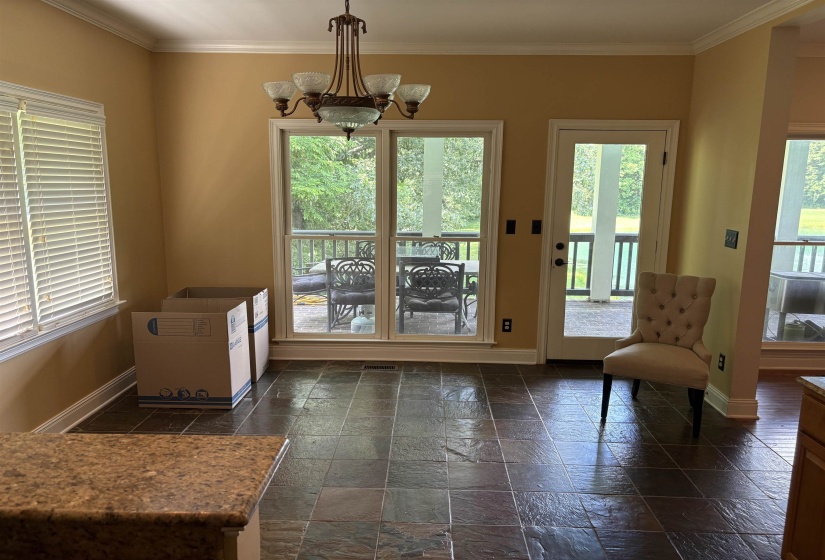 Room featuring dark square tile flooring and a bronze-finish chandelier