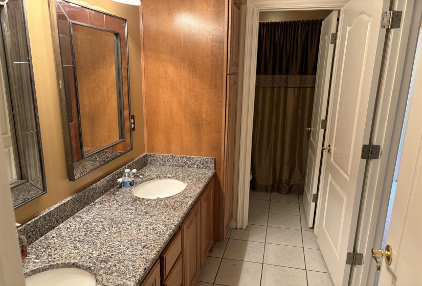 Double vanity with granite countertops, undermount sinks, wood cabinetry, and framed mirrors