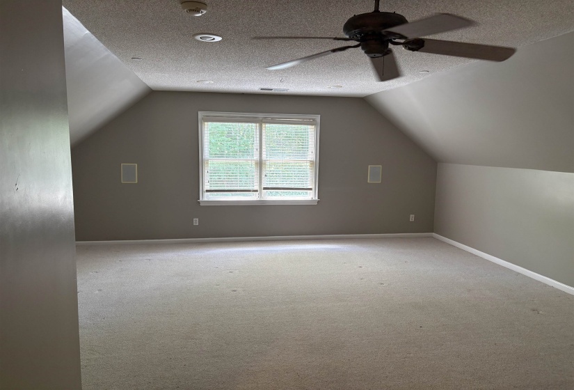 Spacious room featuring sloped ceilings, recessed lighting, and a ceiling fan