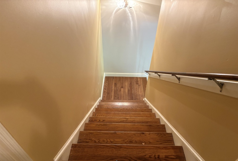 Hardwood staircase with white risers and a contrasting wood handrail