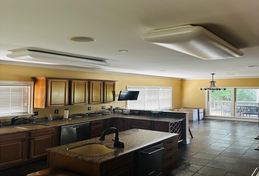 Kitchen featuring dark wood cabinetry, a central island with an undermount sink, and dark stone-look flooring