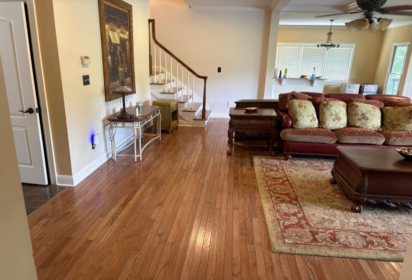 Hardwood flooring extends throughout this open living space, featuring a staircase with white risers and a wood handrail