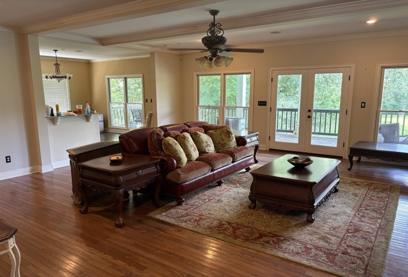 Spacious living area featuring wood-finish flooring, a coffered ceiling, and crown molding