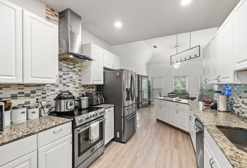 Spacious kitchen featuring white cabinetry, granite countertops, and stainless steel appliances