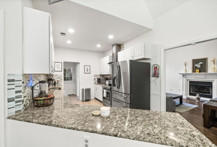 Kitchen featuring a granite countertop, white cabinetry, stainless steel appliances, and a tiled backsplash