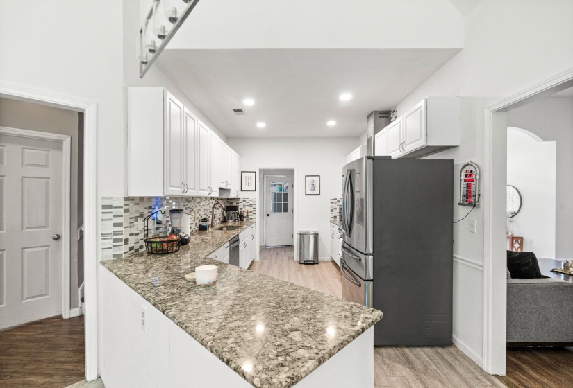 Kitchen featuring white cabinetry, stone-finish countertops, and wood-finish flooring
