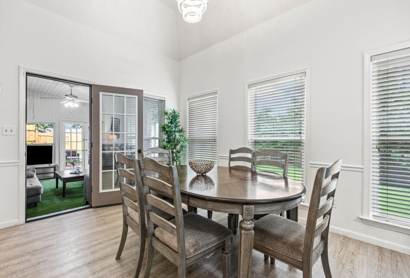 Spacious dining area featuring wood-finish flooring, vaulted ceiling, and multiple windows with blinds