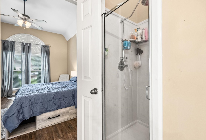 Walk-in shower with clear glass enclosure and gray-toned paneling