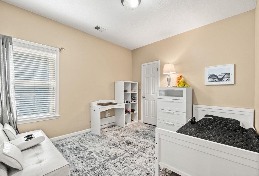 Room featuring neutral wall tones, a large window with blinds, and a textured area rug