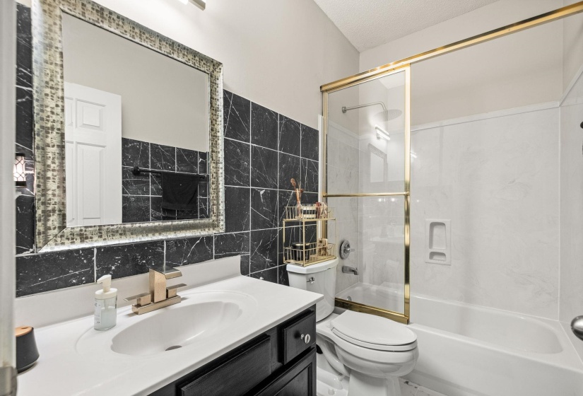 Full bathroom featuring a single vanity with dark cabinetry, integrated sink, and white countertop