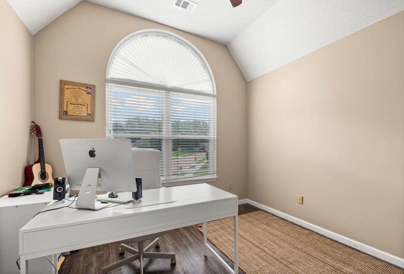 Vaulted ceiling room featuring an arched window with blinds, wood-finish flooring, and neutral wall tones