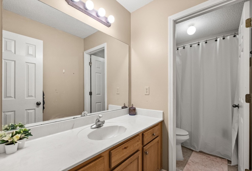 Bathroom vanity featuring a light-toned countertop, integrated sink, and wood-finish cabinetry