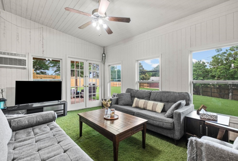 Living area featuring white paneled walls, a vaulted shiplap ceiling, and a ceiling fan