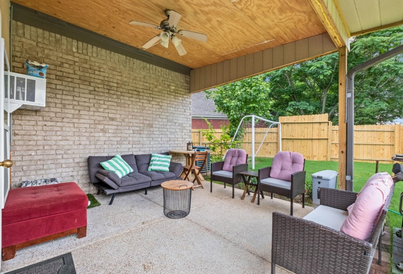 Covered patio featuring a ceiling fan, light-colored brick wall, and concrete flooring