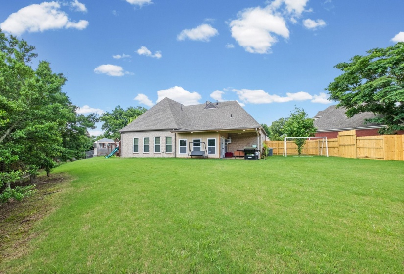Expansive backyard featuring a lush lawn and mature perimeter trees