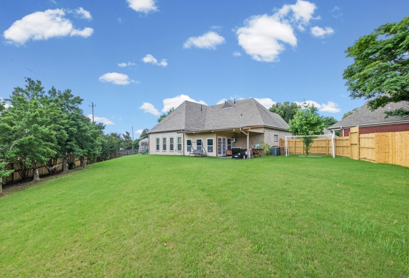Expansive rear yard featuring a manicured lawn and mature perimeter trees