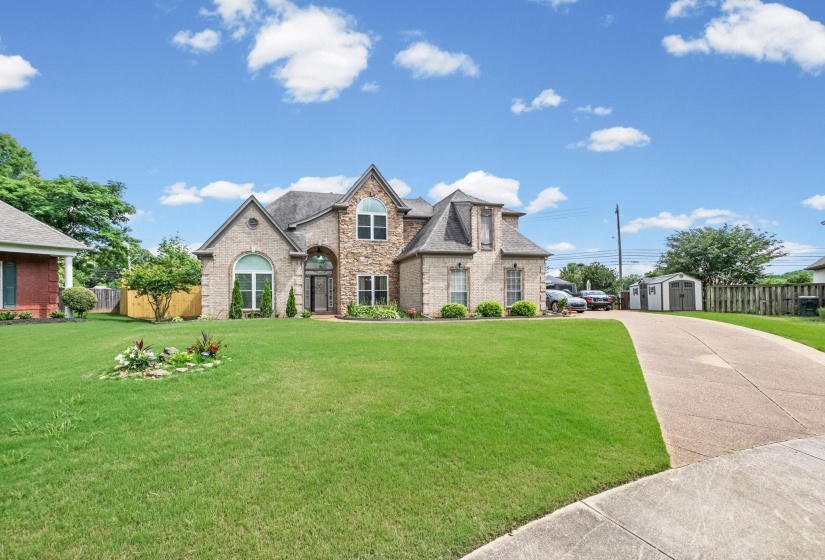 Brick and stone facade residence featuring an arched entryway