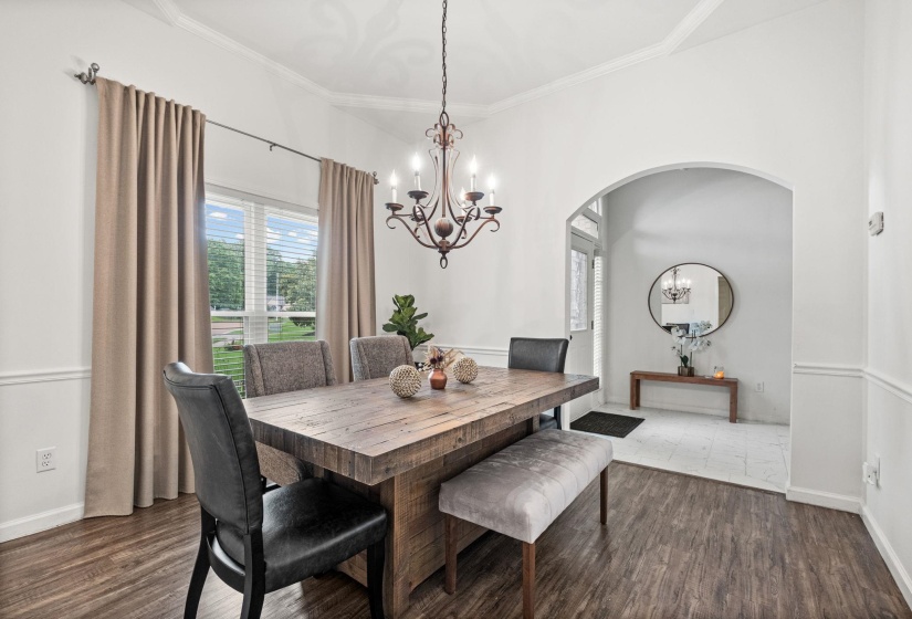 Dining area featuring wood-finish flooring, an arched doorway, and crown molding