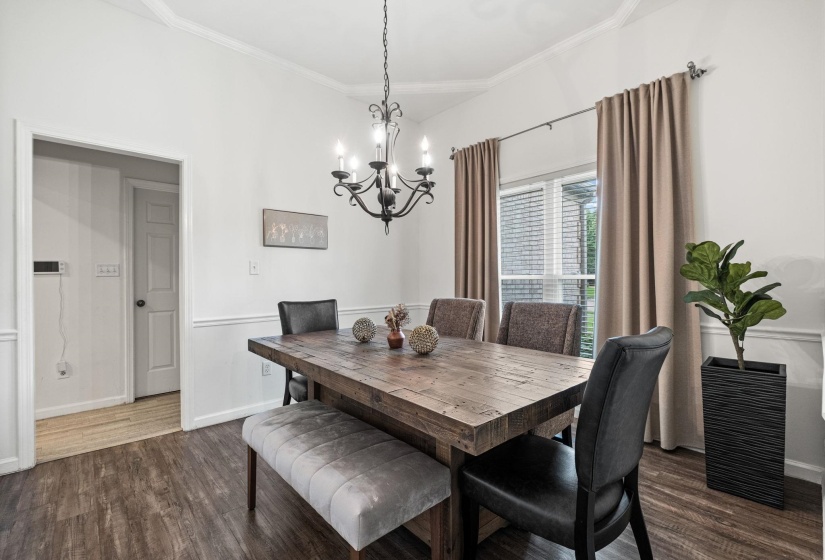 Dining area featuring wood-finish flooring, wainscoting, crown molding, and a chandelier