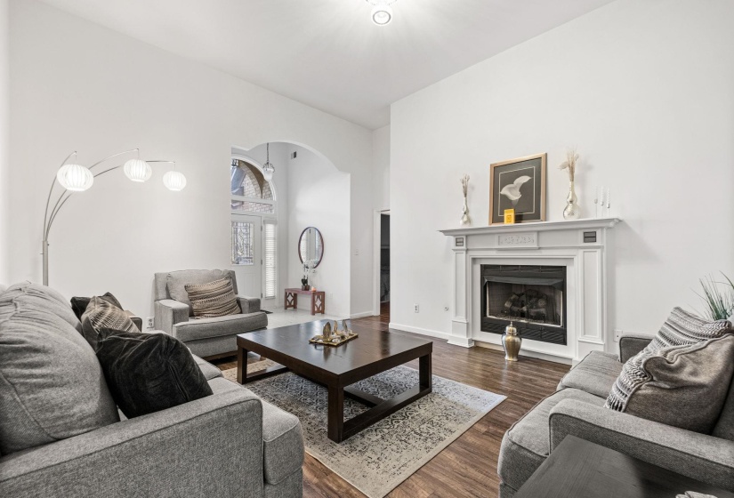 Living area featuring a fireplace with a white mantel, dark wood-finish flooring, and high vaulted ceilings