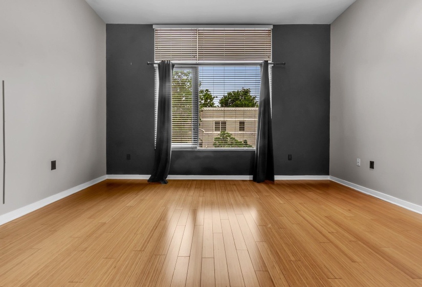 Room featuring wood-finish flooring, a prominent window with blinds, and contrasting wall colors