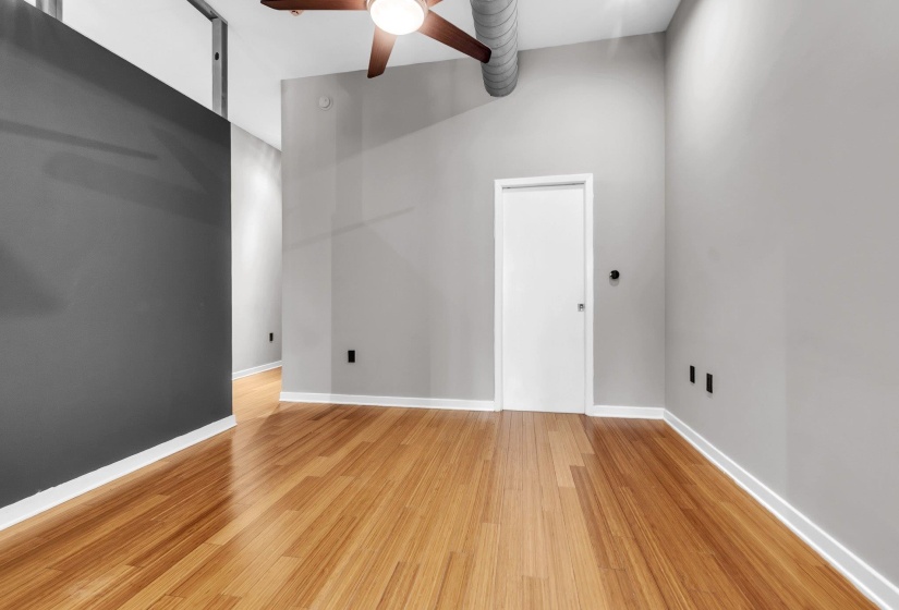 Bright interior space featuring wood-finish flooring, light grey painted walls, white trim, and a ceiling fan
