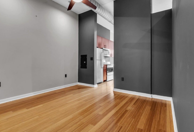 Open-concept living area featuring wood-finish flooring, a ceiling fan, and exposed ductwork