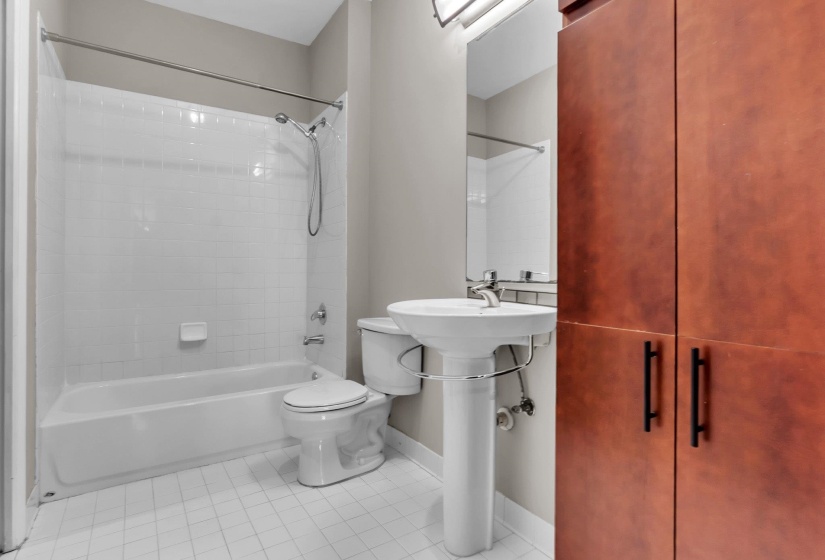 Full bathroom featuring a pedestal sink, white tiled flooring, and a shower/tub combination with subway-style wall tiles
