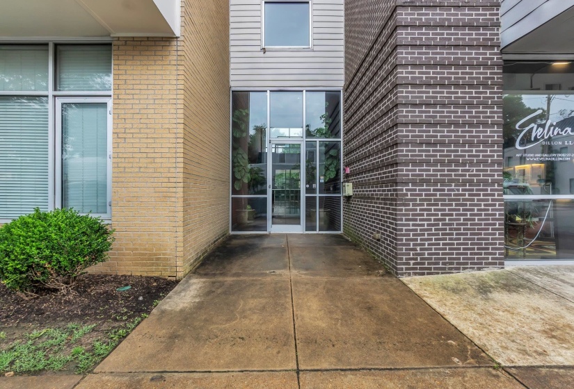 Glass entry doors with aluminum framing, flanked by a light brick facade and a dark brick facade