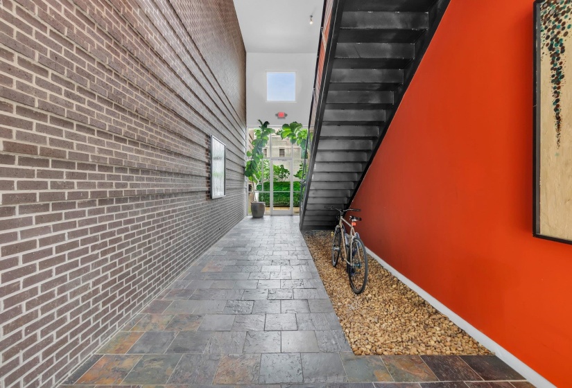 Long entryway featuring a dark brick wall, slate-style flooring, and a vibrant orange accent wall