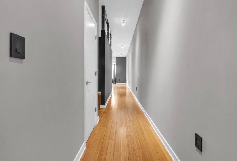 Hallway with wood-finish flooring, light gray walls, and white baseboards