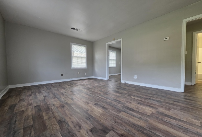 Spacious room featuring wood-finish flooring, light grey walls, and white trim