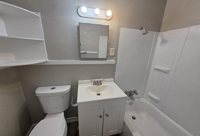 Bathroom featuring a white vanity with integrated sink, chrome faucet, wall-mounted mirror, and overhead light fixture