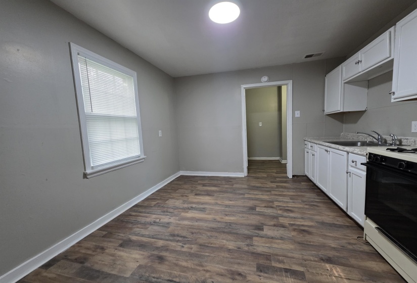 Kitchen featuring wood-finish flooring, white cabinetry, a double basin sink, and a black range