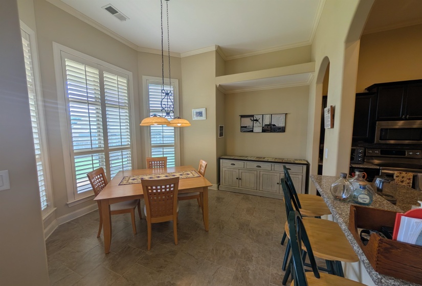 Dining area featuring bay windows with plantation shutters, tile flooring, and crown molding
