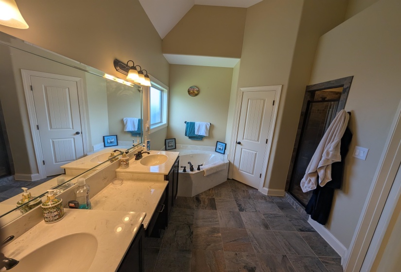 Spacious bathroom featuring dual vanities with integrated sinks, a large soaking tub, and a separate shower enclosure