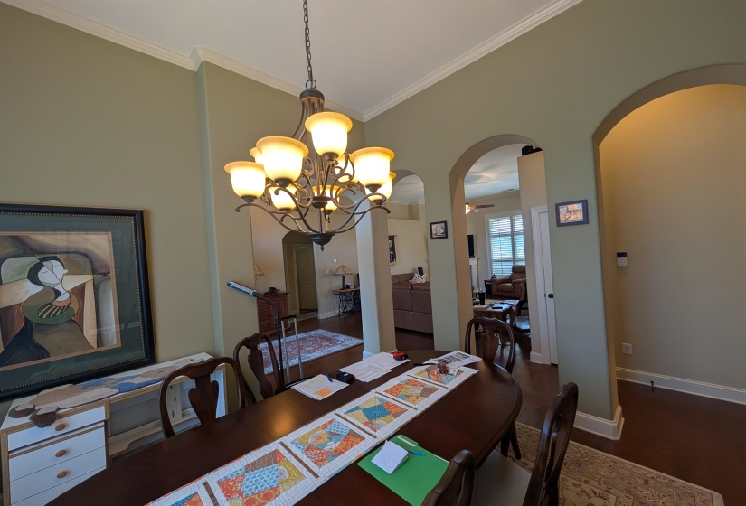 Dining area featuring a bronze-finish chandelier, crown molding, and high ceilings