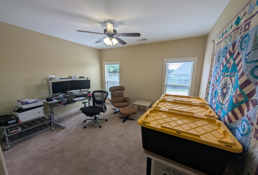 Carpeted room with a ceiling fan light fixture, sloped ceiling, and two windows featuring blinds